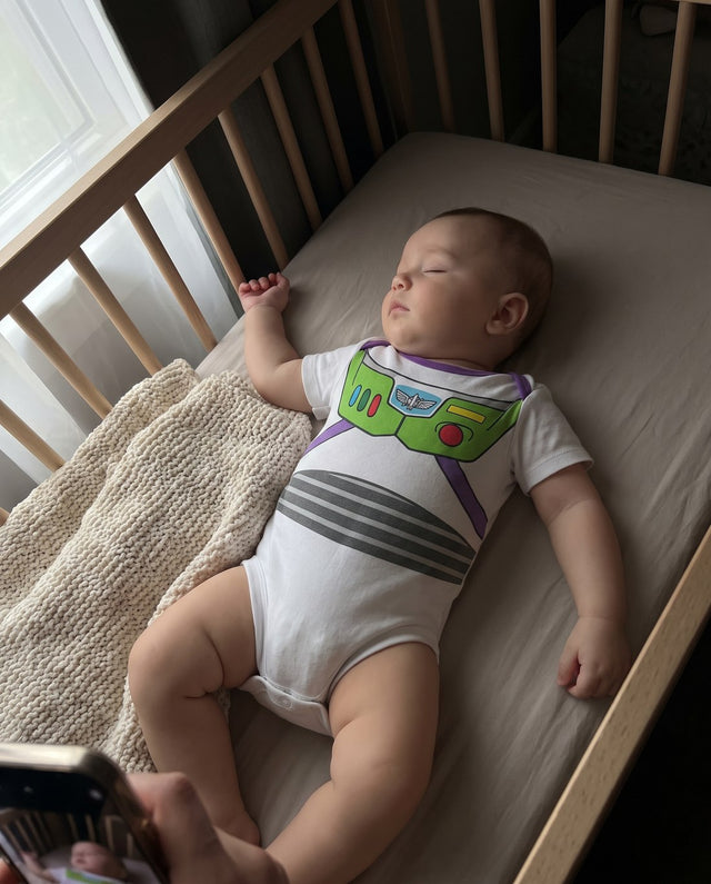 Bebé dormido en la cuna con el body espacial