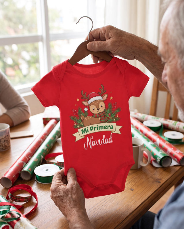 Manos sosteniendo el body rojo en un gancho sobre papel de regalo