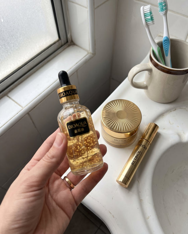 Mano sosteniendo el sérum sobre el lavamanos del baño