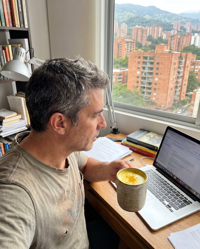 Hombre en su escritorio con una taza de leche dorada